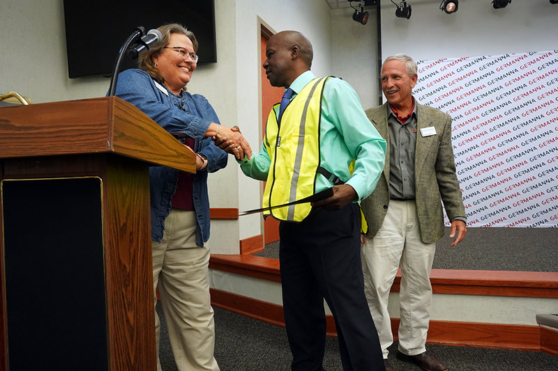 Tina Lance (left) accompanied by Ben Sherman, Business and Career Coordinator (right), shown congratulating a graduate of the Germanna AWS program