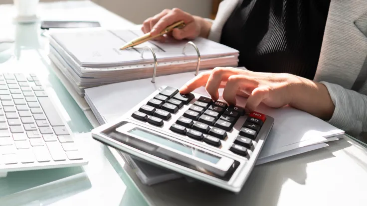 A woman uses a calculator at her desk